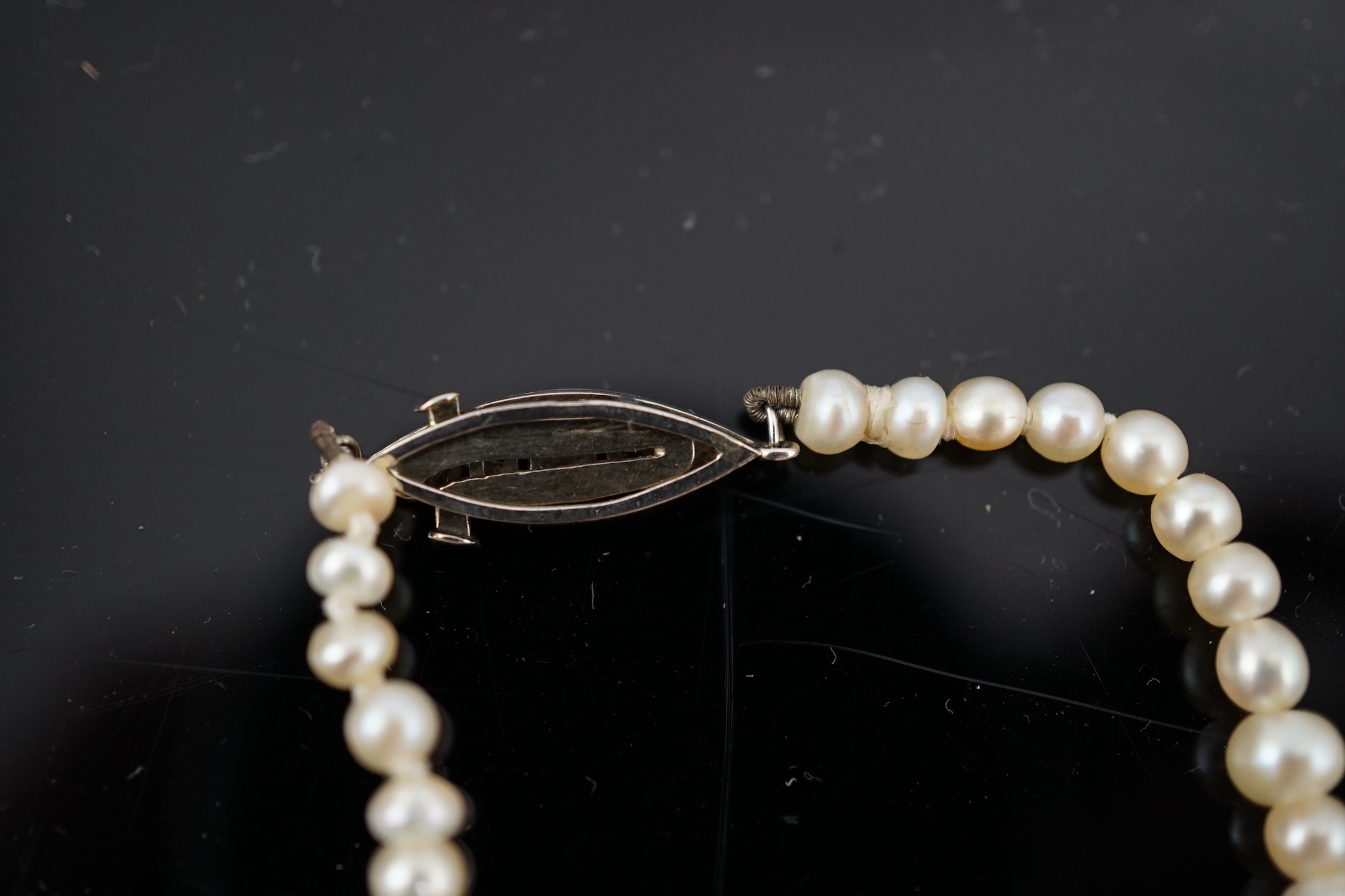 A late 19th century single strand graduated natural saltwater pearl necklace, with a French 18ct white gold and millegrain set diamond marquise shaped clasp